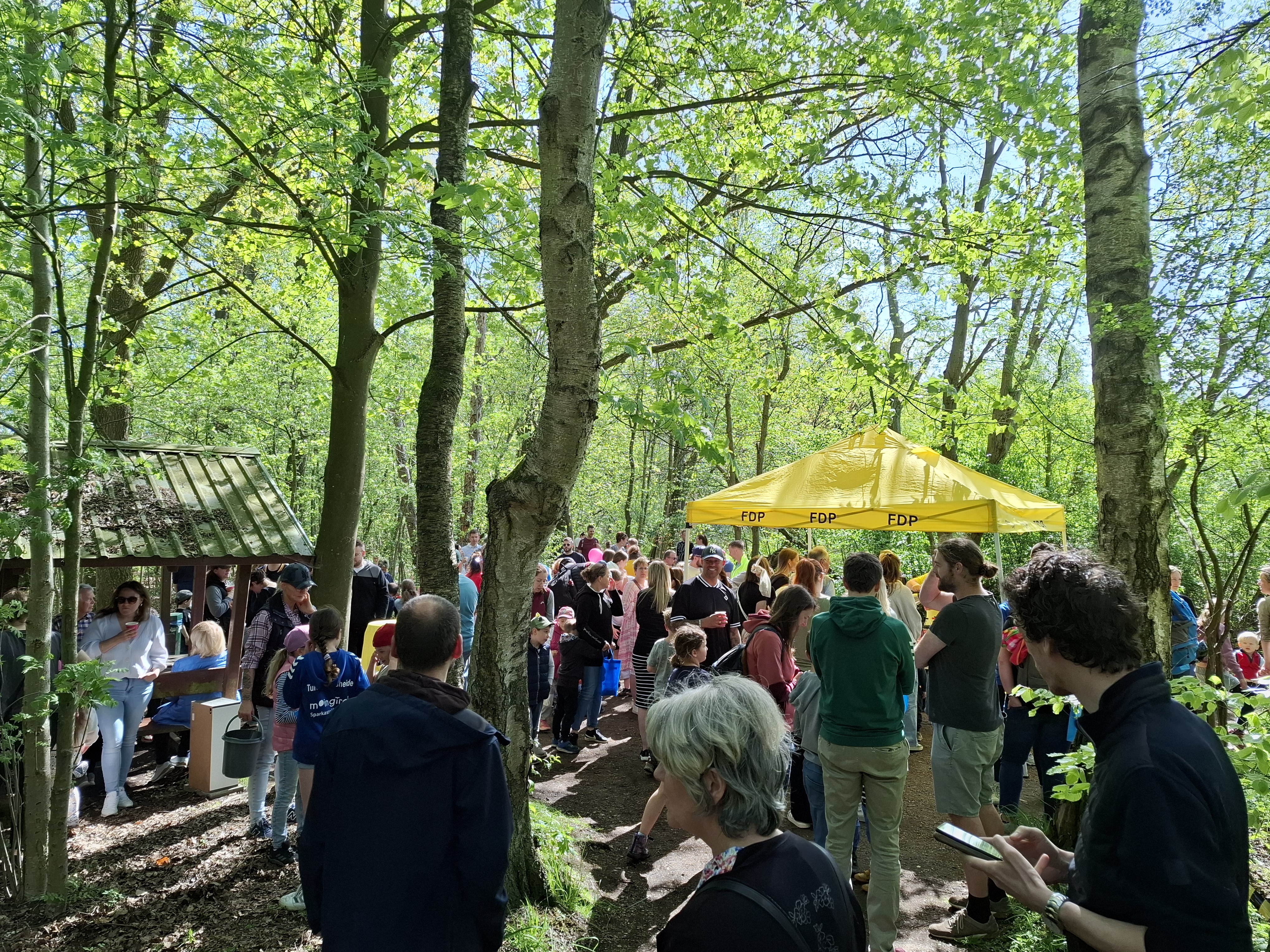 Viele Menschen sammeln sich nahe eines FDP-Zeltes an der Alsterquelle in Henstedt-Ulzburg